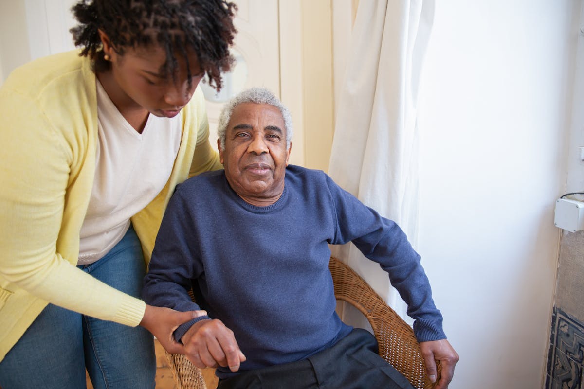 A young woman helping an elderly man at home