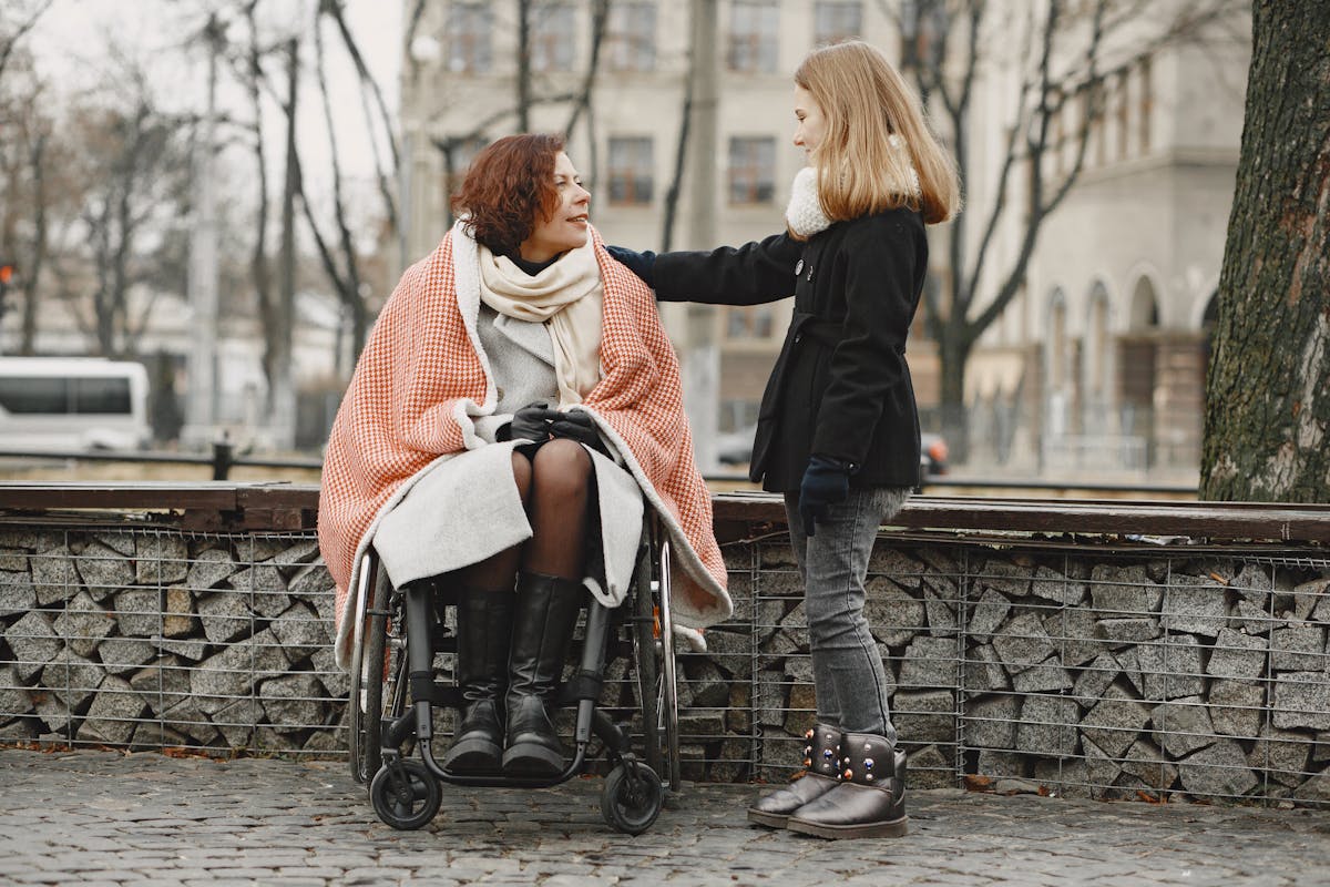 A woman in a wheelchair with a supportive companion outdoors